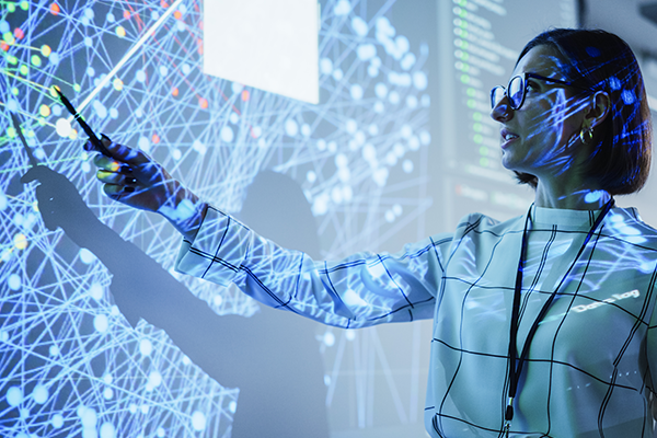 A person interacting with complex digital data visualizations projected on screens, illustrating a high-tech and analytical environment.